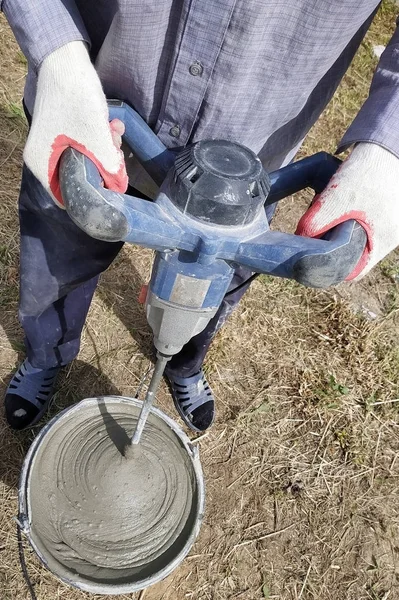 Le maître sur le chantier mélange de la colle avec de l'eau pour poser le mur de blocs de gaz . — Photo