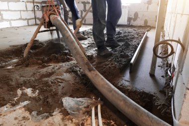 Employee performs sand-cement floor screed, Sand-cement floor screed for heating.