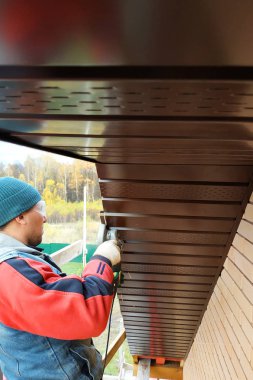 İşçiler evin çatısının altına saçak döşüyorlar.