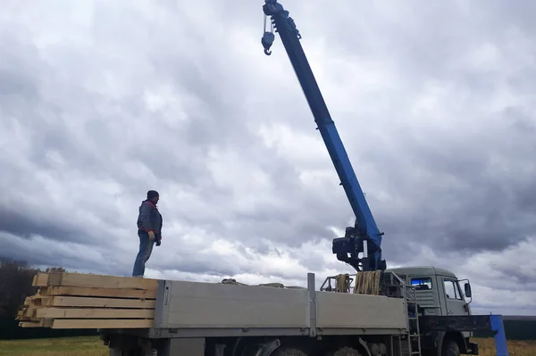 The crane lowers the roof construction boards.