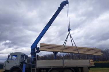 İnşaat alanına vinç, manipülatör ve işçiler tarafından beslenen kargo tahtaları..