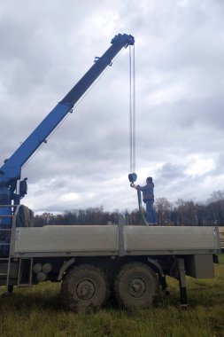 İnşaat alanına vinç, manipülatör ve işçiler tarafından beslenen kargo tahtaları..