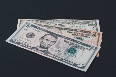 Beş, on ve yirmi dolarlık banknotlar siyah arka planda yatıyor..
