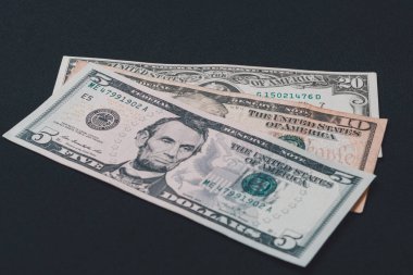 Beş, on ve yirmi dolarlık banknotlar siyah arka planda yatıyor..