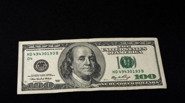 Yüz Amerikan doları siyah bir arkaplanda, yazıtlar için boş alan..