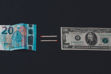 Euros and dollars on a black background, banknotes comparison.