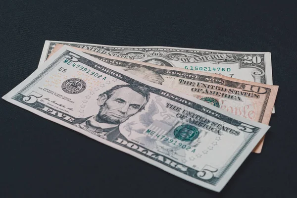 Öt, tíz és húsz dolláros bankjegyek fekszenek fekete alapon.. — Stock Fotó