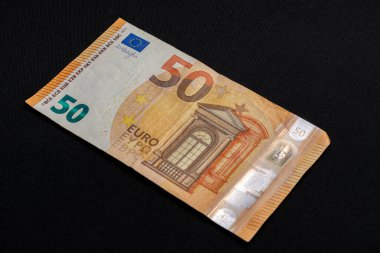 Fifty euro denominated paper money on a black background.