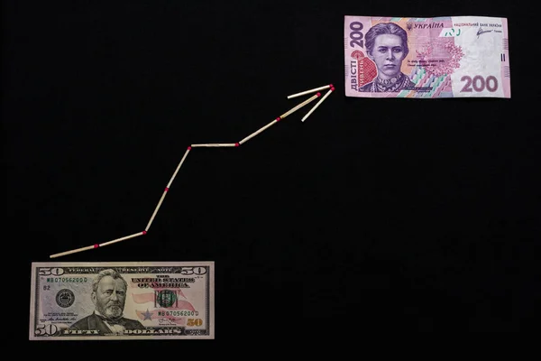 Grivna ucraniana y dólar estadounidense con flecha sobre fondo negro . — Foto de Stock