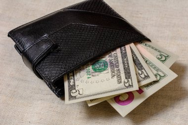 A dollar bill in the size 5 of a black wallet.
