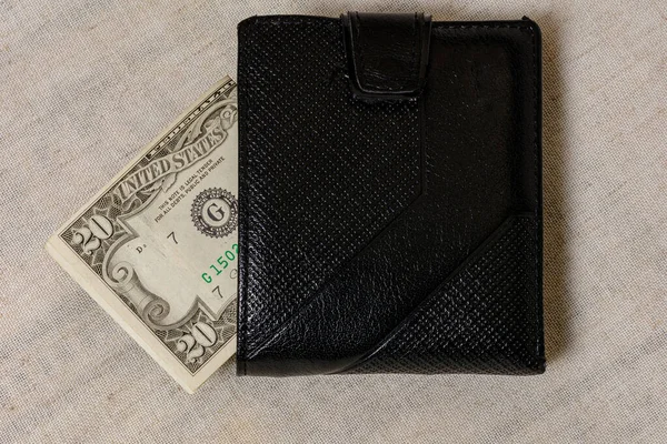 20 dollars sticking out of a wallet of dark leather on a gray background. — Stockfoto