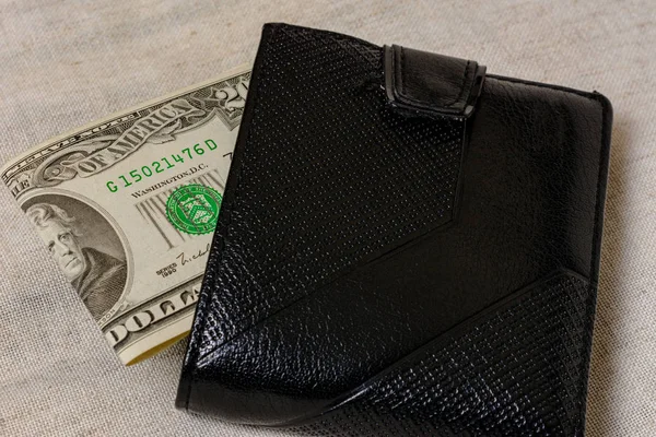 20 dollars sticking out of a wallet of dark leather on a gray background. — Stock fotografie