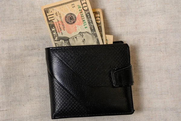 10 dollars lying in a black leather wallet on a gray background. — Stock fotografie