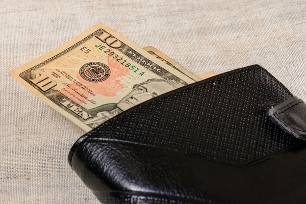 10 dollars lying in a black leather wallet on a gray background. — Stock fotografie