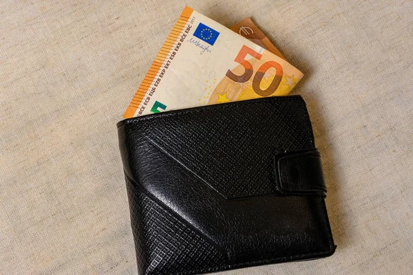 Банкноты евро и черный бумажник на сером фоне — стоковое фото