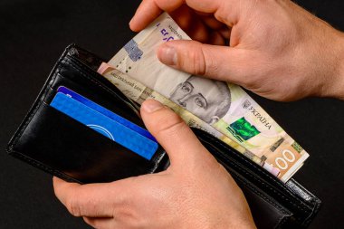 Closeup in the hands of a man's wallet when he pulls out a 500 hryvnia banknote.
