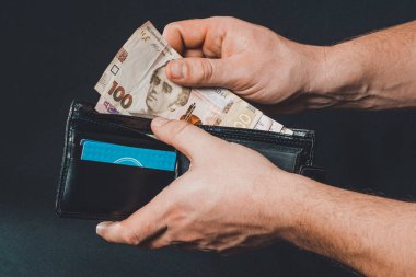 Ukrainian hryvnia in a black purse, a man holds in his hands.