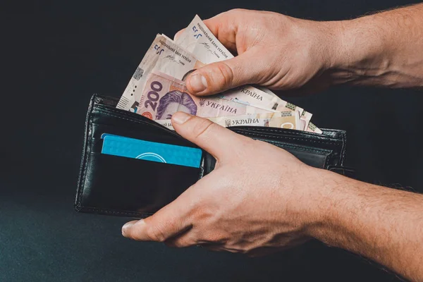 Ukrainian hryvnia in a black purse, a man holds in his hands. — Stock Fotó