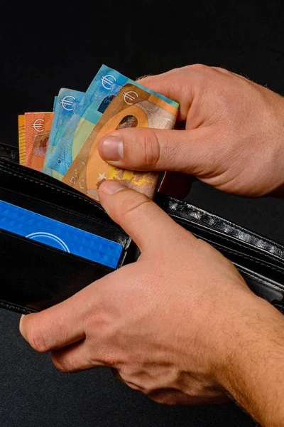 Man hand pulling money from wallet, black background and black wallet. — Stock Fotó