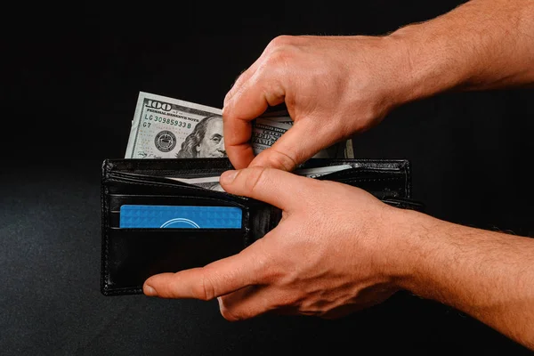 Man on black background holds in his hands a wallet with dollars close up. — Stock Fotó