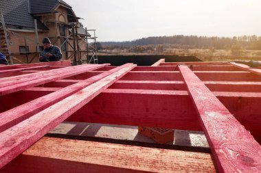 Çatı kirişlerinin çatı sistemine ahşap kirişler döşenmesi, işçi kirişlere çivi çakıyor. 2020