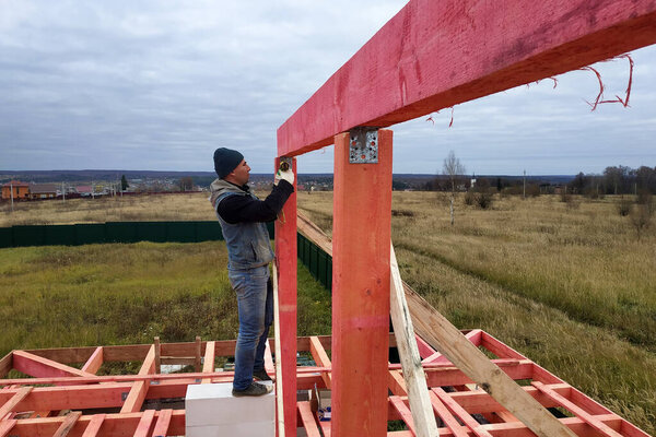 Rafters wooden against the blue sky, the master is working on the installation of bars.2020