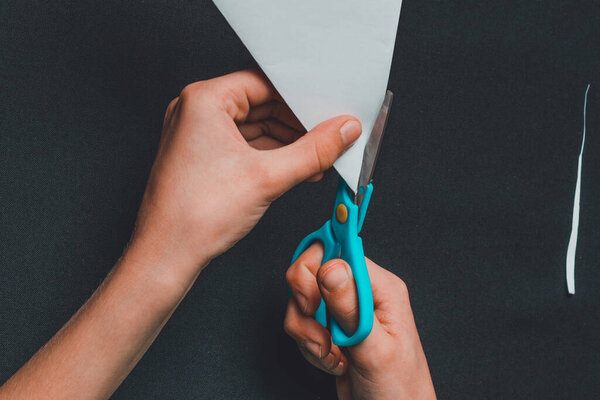 A boy on a black desk works with white paper. 2019