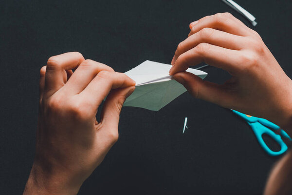 The boy of school age is engaged in application works, cuts white paper. 2020