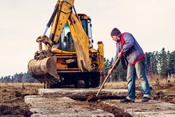 The shovel worker cleans the soil after digging the excavator, laying the road. 2019