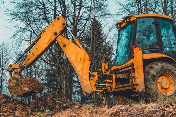 Ormanın ortasında yaşlı sarı bir kazıcı su toplamak için bir kepçe çukuru kazıyor. 2020