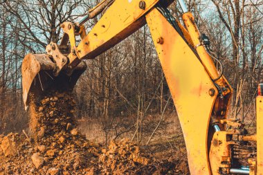 Ormandaki işçi ve sarı kazıcı su almak için bir çukur kazıyor. 2020