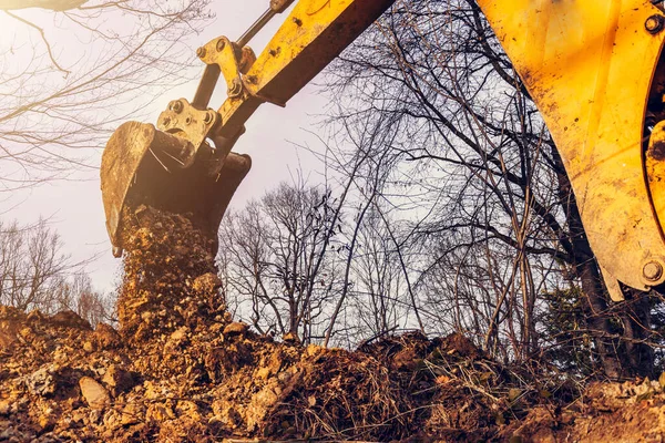 The excavator performs excavation work by digging the ground with a bucket in the forest.2020