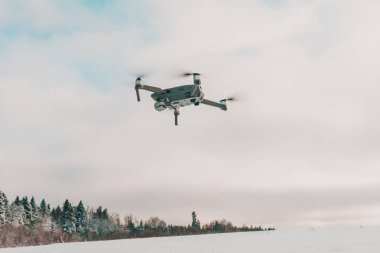 Gökyüzünde uçan küçük gri dron, bulutlu bir arka planda kuadkopter. 2020