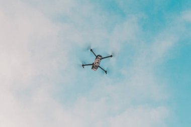 Gökyüzünde uçan küçük gri dron, bulutlu bir arka planda kuadkopter. 2020