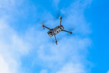 Gökyüzünde uçan küçük gri dron, bulutlu bir arka planda kuadkopter. 2020