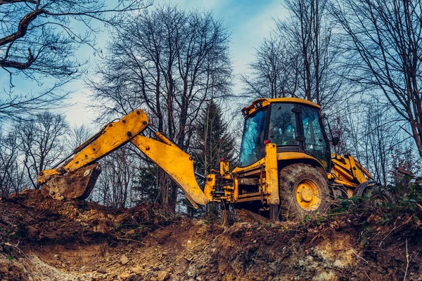 森林中央的一台黄色旧挖掘机在挖一个勺坑取水 — 图库照片