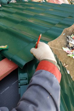 İşçi, evin çatısına metal bir kiremit yerleştirir ve takar. 2020