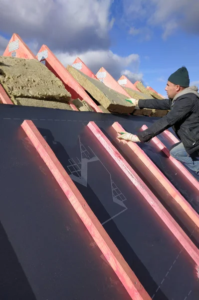 Insulation and waterproofing of the roof surface, the worker nails the film to the boards.2020