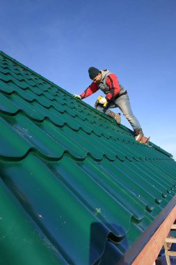 Bir çatı işçisi çatıya metal bir kiremit takar. 2020
