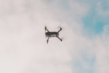 Gökyüzünde uçan küçük gri dron, bulutlu bir arka planda kuadkopter. 2020