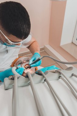 Hasta diş macunuyla bir diş sandalyesine oturur, doktor tartı çıkarır. 2020