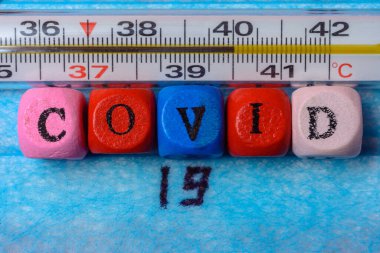 Maske arkaplanındaki koronavirüs ve yüksek sıcaklık termometresi. 2020