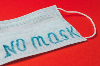 Maskeye kazınmış koronavirüs, kırmızı arka planda maske yok. 2020