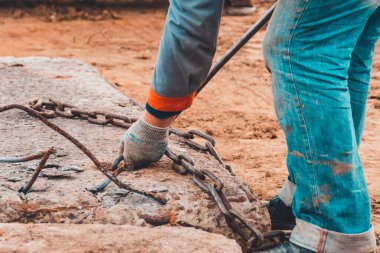 İşçi yoldaki beton levhaları taşımak ve yüklemek için kazıcı kovasına zincir takıyor. 2019