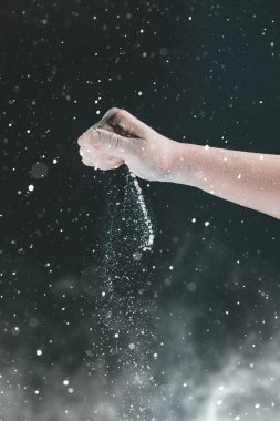 Siyah arka planda, bir kadının eli 2020 'de pişirmek için kar gibi beyaz un döker.