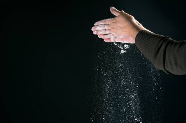 Mutfakta yemek pişiren bir kadının eli, siyah arka planda izole edilmiş ekmek pişirmek için beyaz toz unu un masası döker.