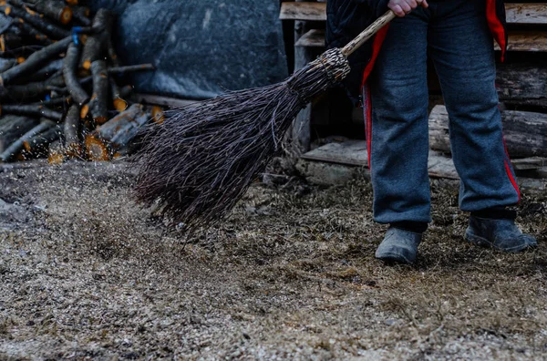 Cleaning in the yard in late fall, a woman with a broom cleans her yard. 2019
