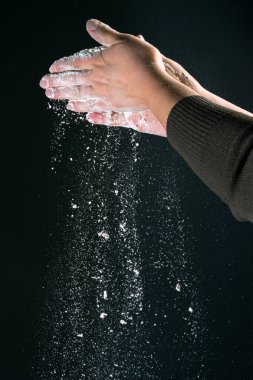 Mutfakta yemek pişiren bir kadının eli, siyah arka planda izole edilmiş ekmek pişirmek için beyaz toz unu un masası döker.