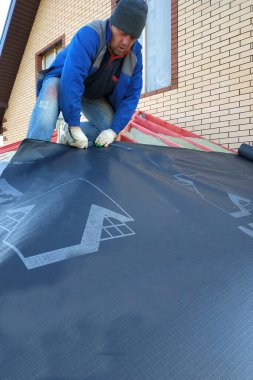 Çatı yalıtım malzemesi ile kaplı, çatının tabanı. 2020 'de çatıya çekiç döşeyen işçiler.