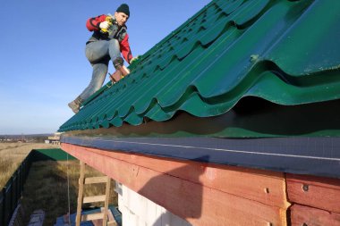 A rooftop worker attaches a metal tile to the roof base.2020 clipart